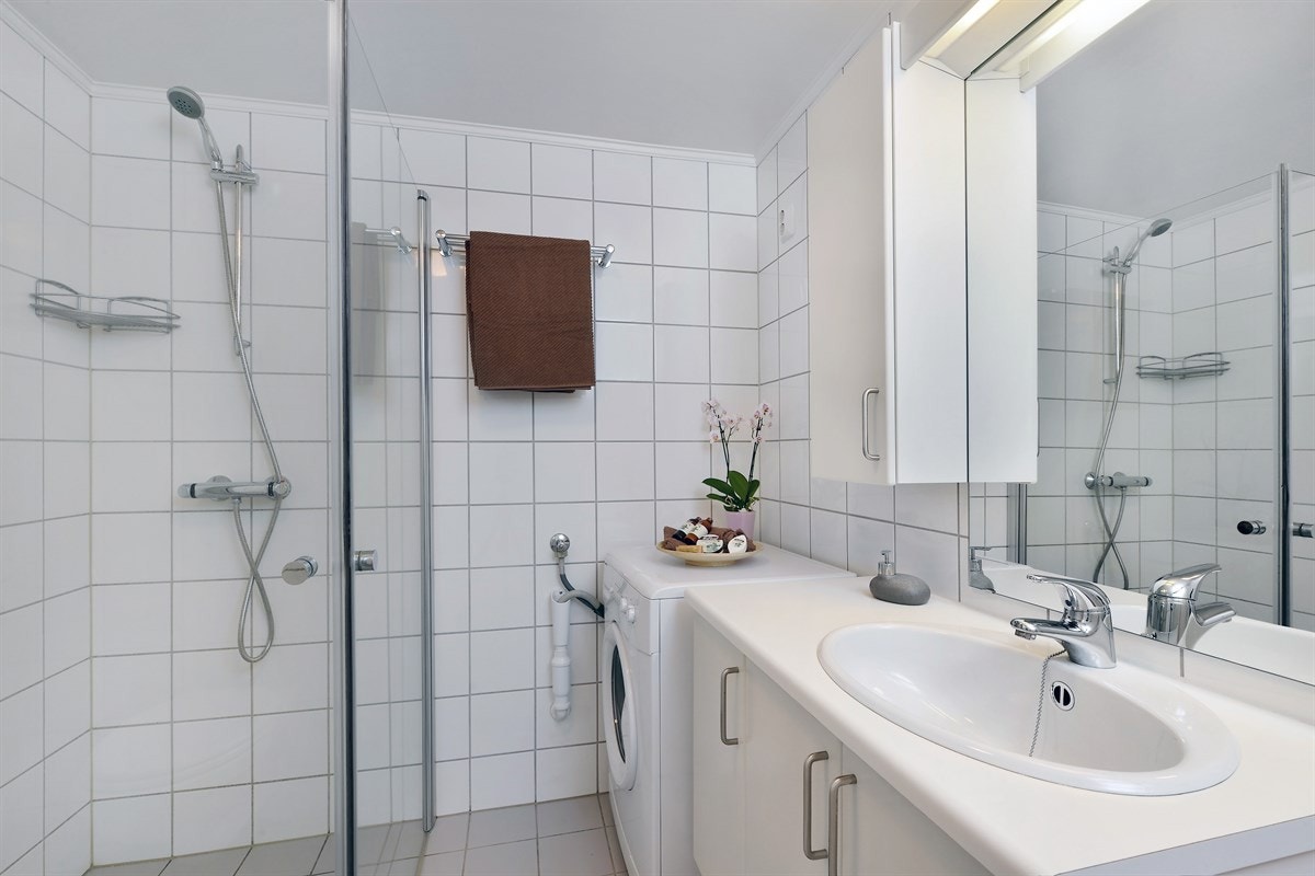 Badet har vegghengt toalett og dusjhjørne med nyere, innfellbare glassdører. Det medfølger vaskemaskin. Galleribilde