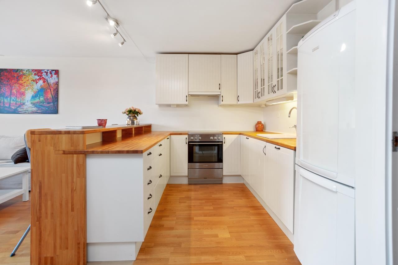 Kjøkkeninnredning med hvite profilerte fronter og bøk benkeplate. Galleribilde