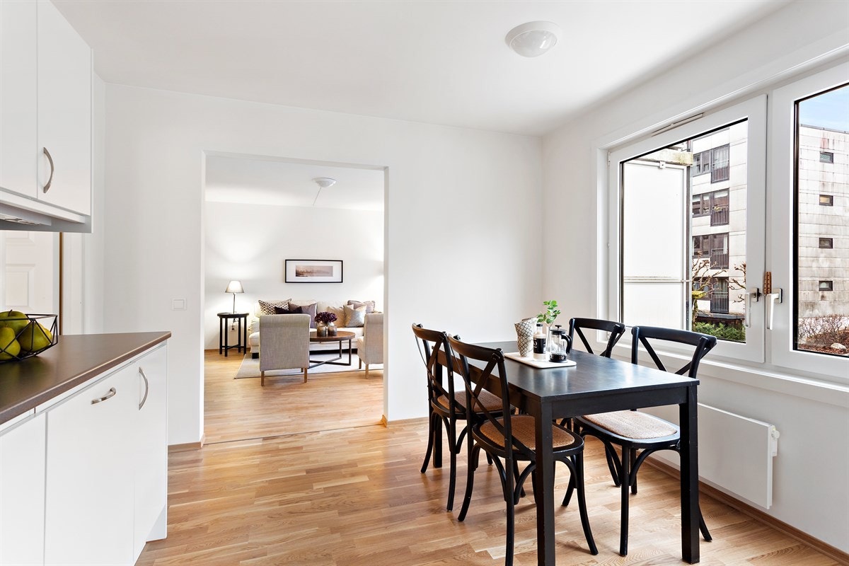 Hvit kjøkkeninnredning med enkel oppvaskkum, laminat mellom overskap og laminert benkeplate. Galleribilde