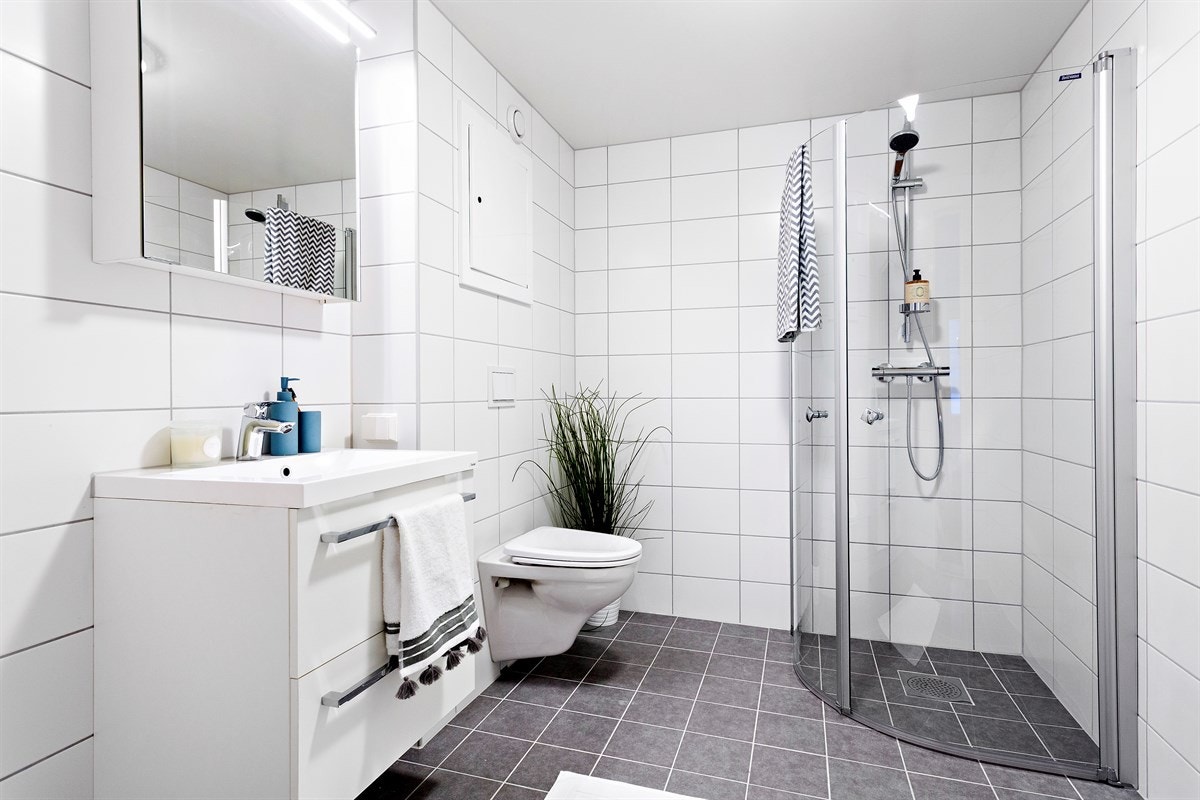 Hovedbadet består av åpen dusjplass med slagdører, heldekkende servant i skapinnredning, speilskap, vegghengt wc og opplegg for vaskemaskin. Inngang fra hovedsoverom. Galleribilde