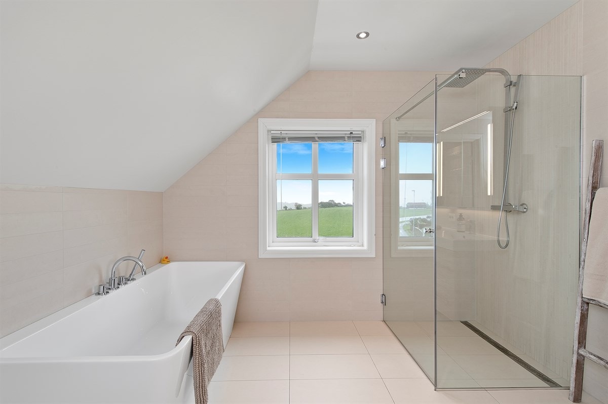 Det er en moderne baderomsinnredning med heldekkende, dobbel servant og skuffer og skap for oppbevaring. Galleribilde