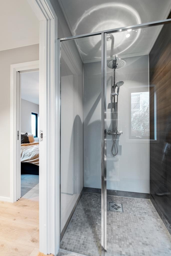 Badet har fliser på gulv og er innredet med dusj, vegghengt toalett og seksjon med vask. Galleribilde