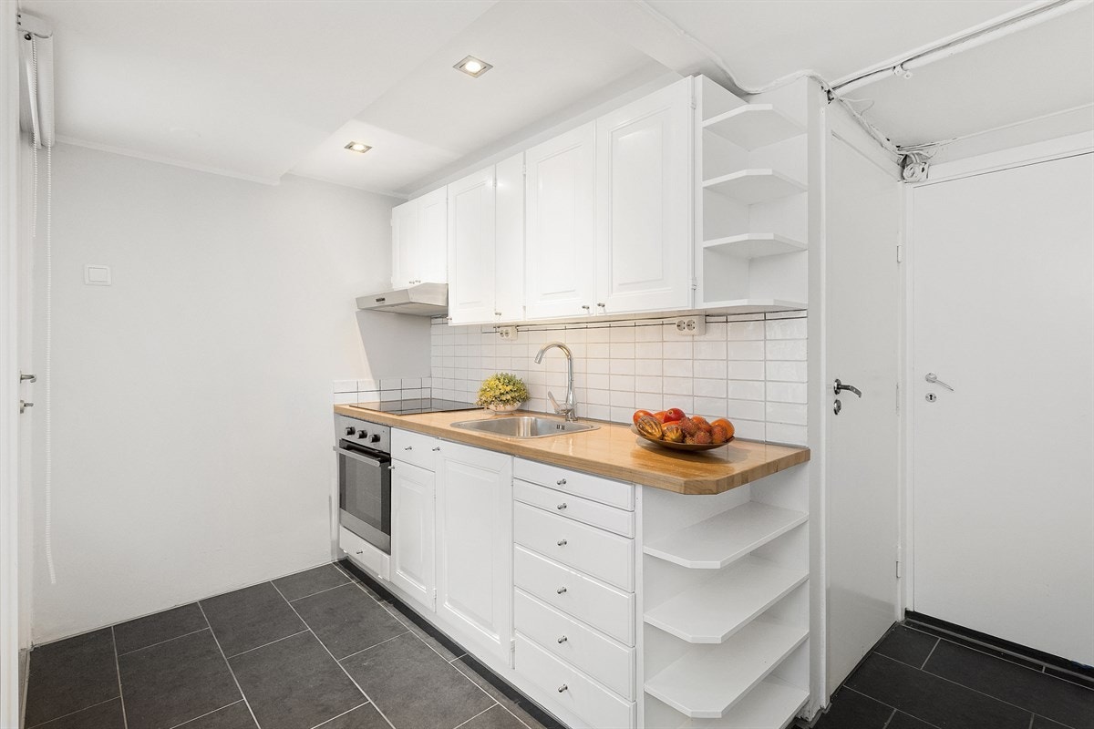 Kjøkkenet i praktikantdelen har mørke fliser på gulv og en nyere innredning. Galleribilde