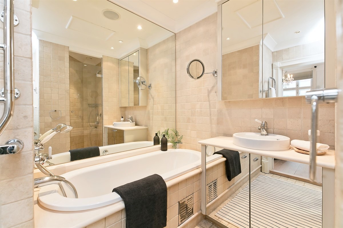 Bad I i tilknytning til hovedsoverom er flislagt på vegger og gulv i delikate farger Galleribilde