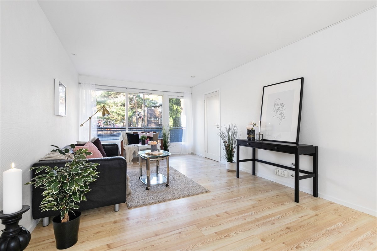 Stuen er pen med laminatgulv og hvitmalte vegger samt direkte utgang til balkong. Galleribilde