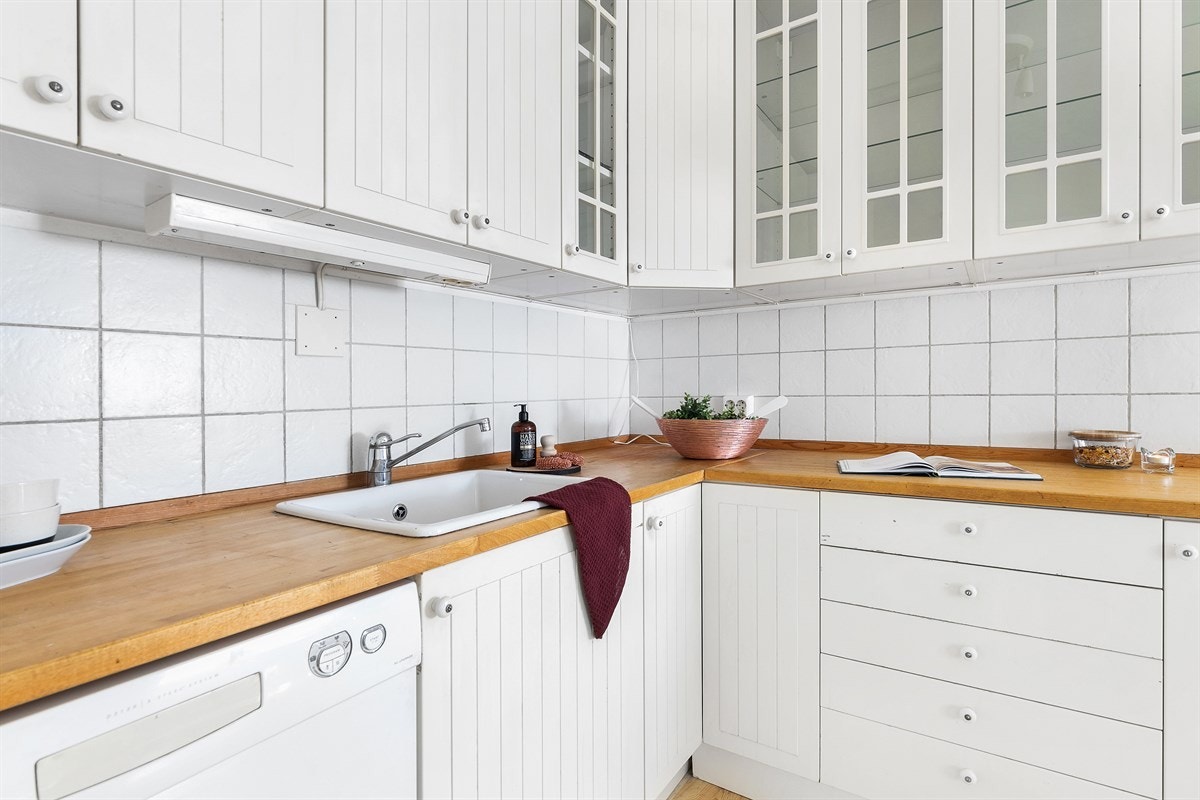 Over benken er det hvite fliser, og over kokesonen er det montert en ventilator. Galleribilde