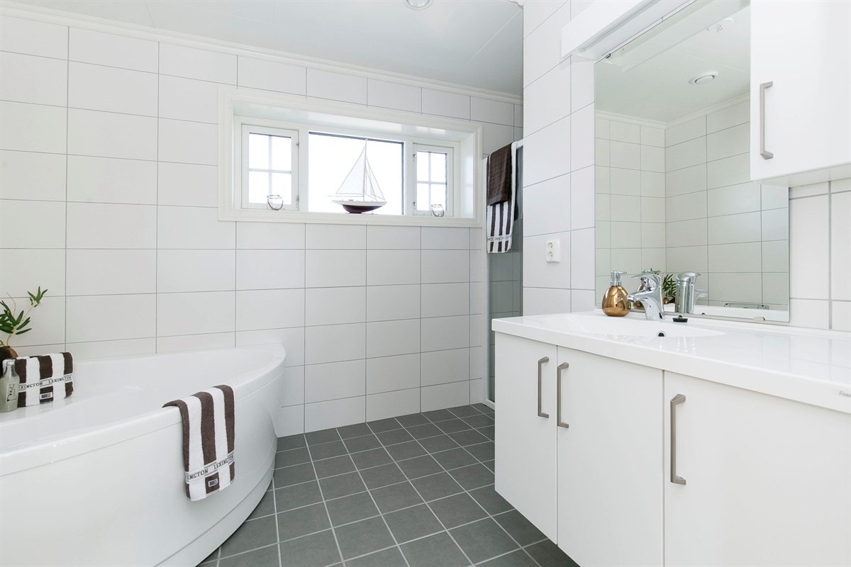 I boligens 2. etasje har du et nydelig bad i lyse farger, med varmekabler i gulv, hjørnebadekar og dusjnisje Galleribilde