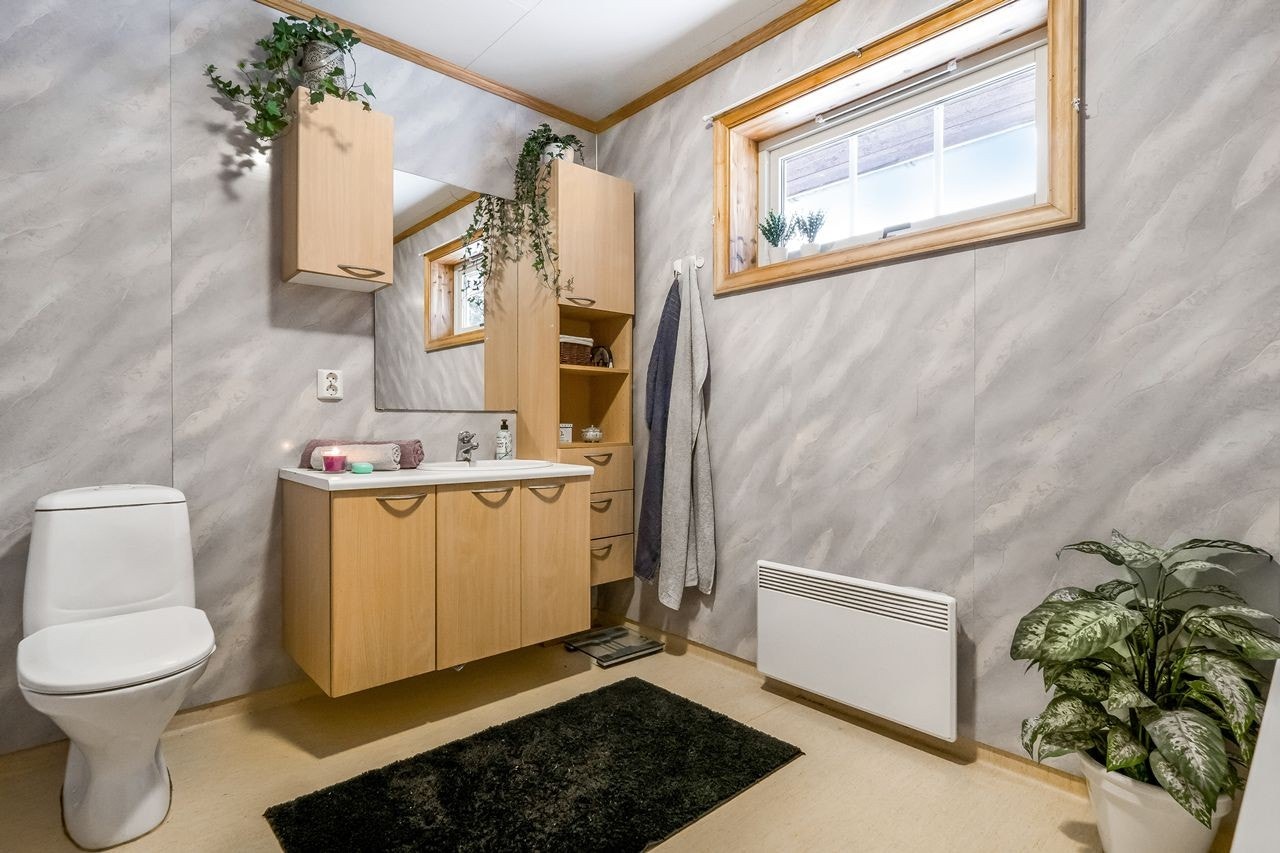 Badet har innholdsrik innredning med servant, underskap, overskap speil og høyskap. Inneholder ellers toalett og badekar med dusj Galleribilde