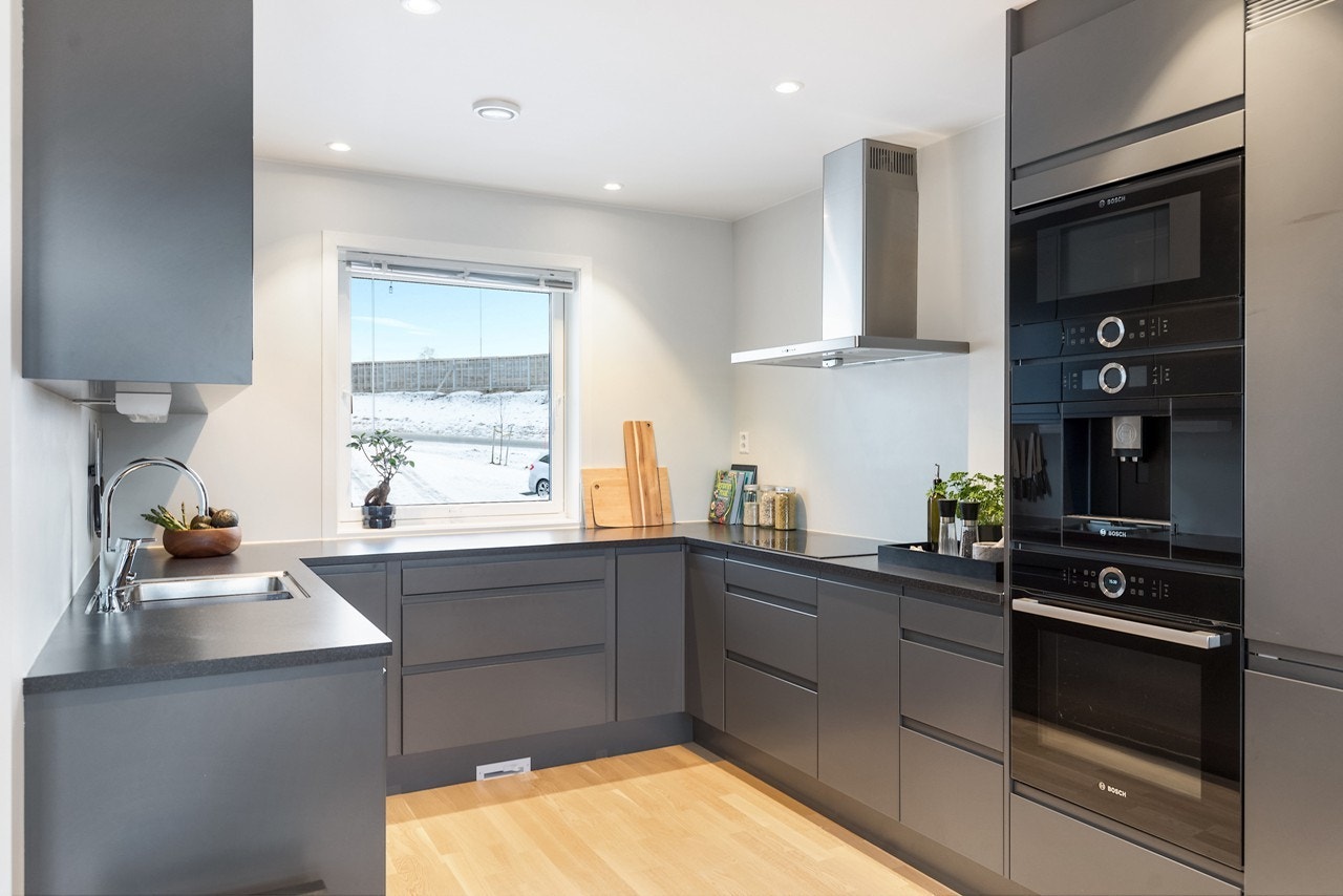 Plasseringen av kjøkkenet i hesteskoform gir en funksjonell arbeidssone med rikelig med skap- og benkeplass Galleribilde