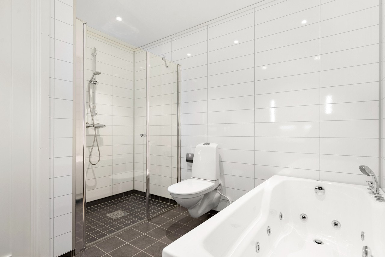 Badet er blant annet oppgradert med boblebad, større fliser, glassdør foran dusjhjørnet, påkostet Corian benkeplate og stilfullt design servantbatteri Galleribilde