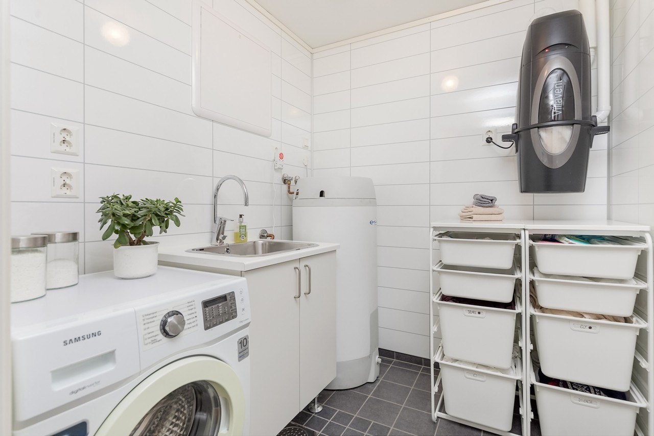 Boligens vaskerom ligger også i sokkeletasjen. Rommet har benkeplate med nedfelt utslagsvask i stål og tilhørende underskap med glatte fronter. Det er opplegg for vaskemaskin og sentral for støvsuger Galleribilde