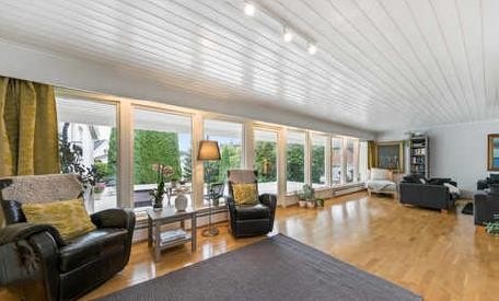 Stor fellesstue i 1.etasje med store vindusflater og utgang til terrasse Galleribilde