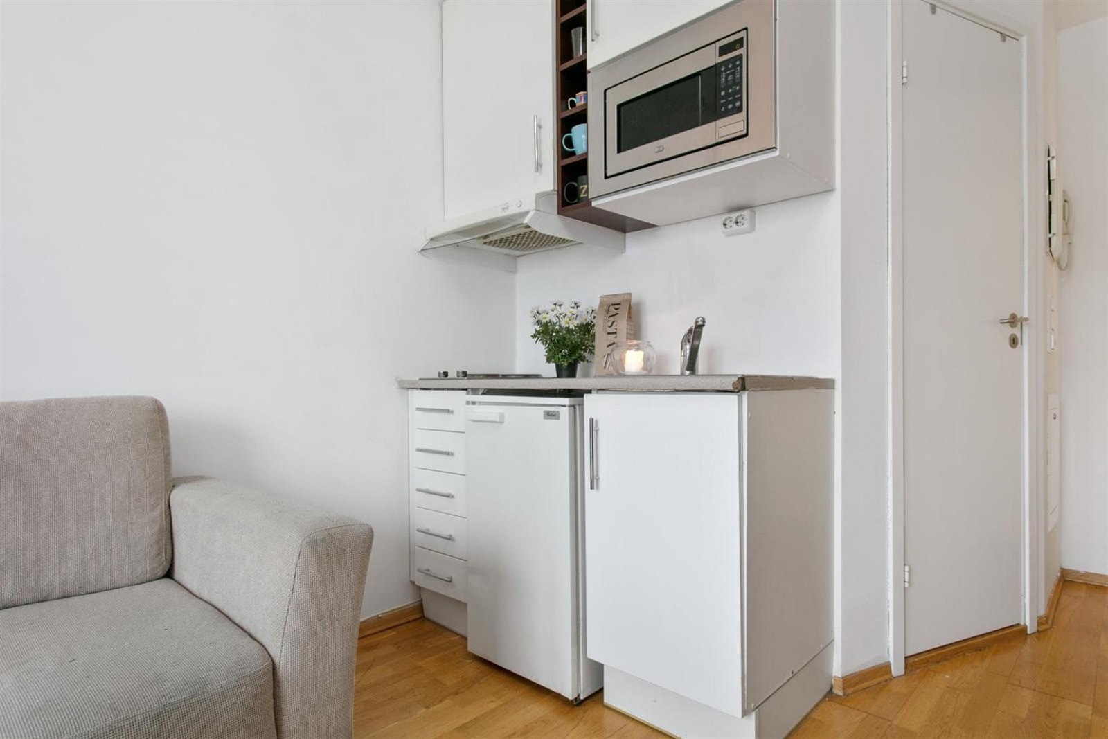 Praktisk kjøkken med integrete hvitevarer som kokeplate, kjøleskap og mikrobølgeovn. Galleribilde