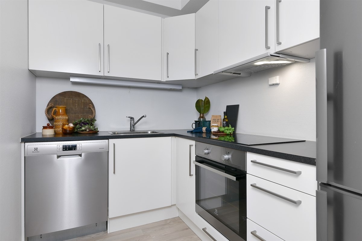 Frontene er lyse, mens benkeplaten er laminert og mørk, samt utstyrt med nedfelt vaskekum. Kjøkkenet har integrert stekeovn, koketopp og oppvaskmaskin. Galleribilde