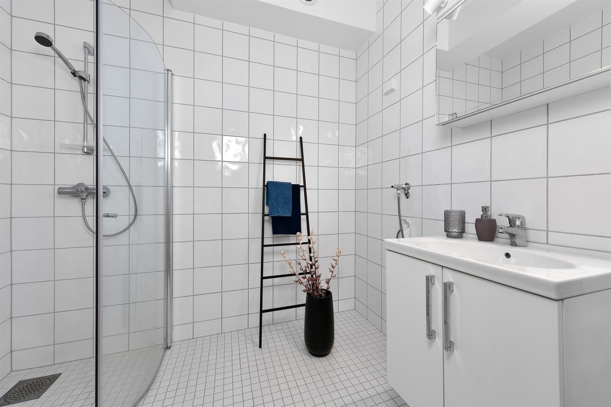 Badet fremstår som delikat med ulike, lyse fliser, gulvvarme og pen innredning. Innredningen består av servantskap og speilskap med overbelysning. Galleribilde