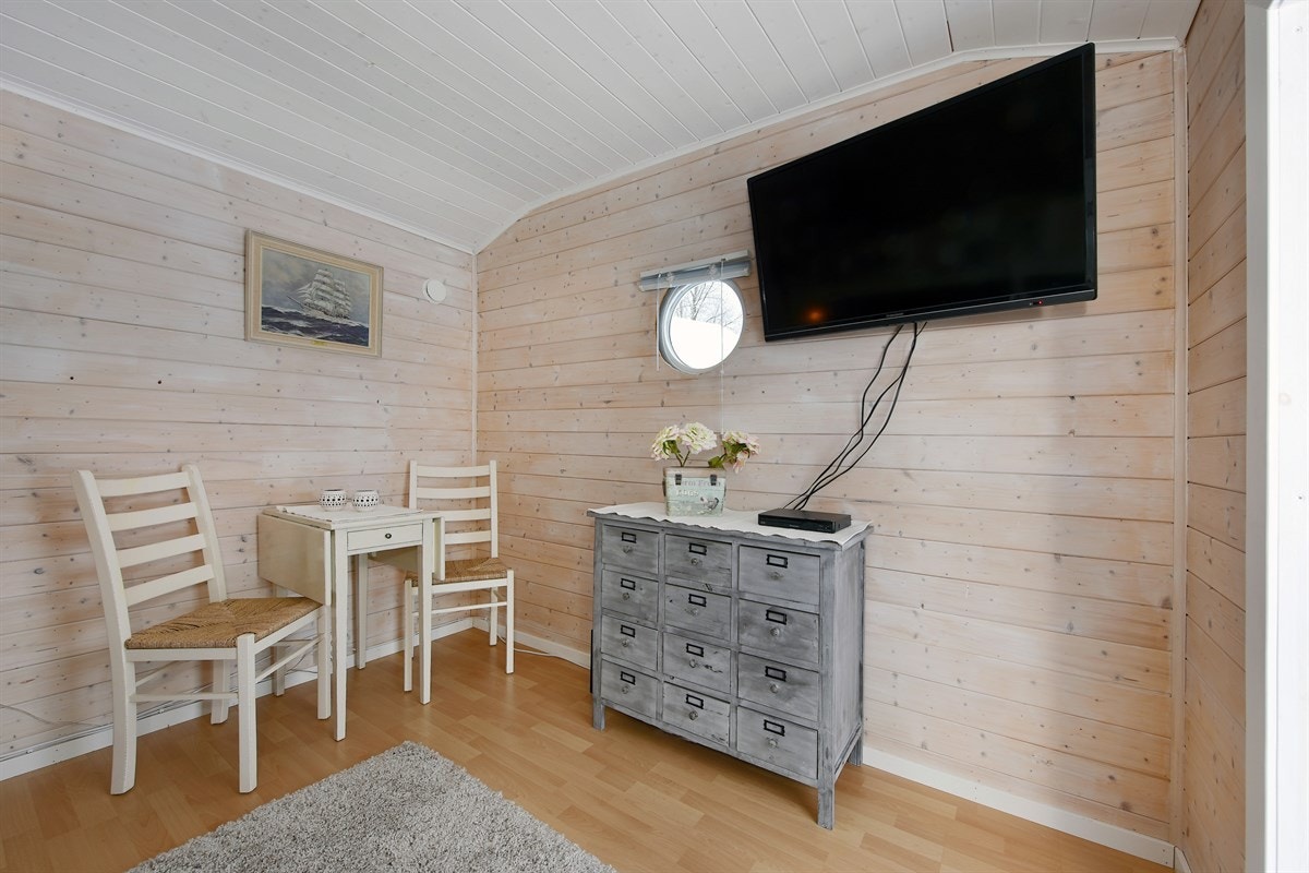 Annekset/dukkestue er innredet med TV og sittegruppe. Galleribilde