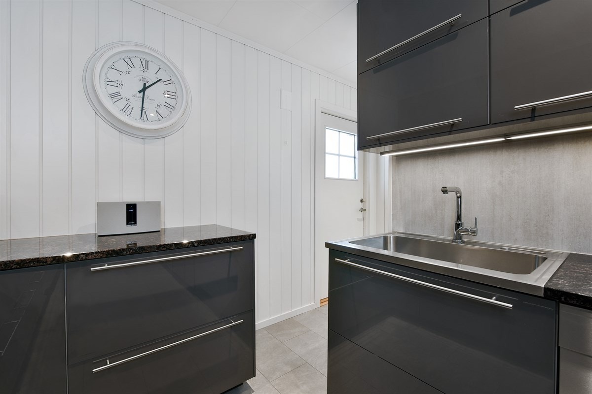 Videre er det benkebelysning, stilige fliser over benk og avtrekksvifte i stålhette over nedfelt platetopp fra Miele. Galleribilde