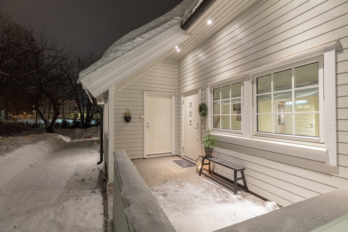 I forbindelse med inngangspartiet finnes det en koselig, delvis overbygd adkomstterrasse på ca. 10 kvm. Terrassen har downlights i takutspring, tremmegulv og hvitmalt rekkverk. Fra uteplassen er det direkte adkomst til utvendig bod på ca. 5 kvm. Galleribilde