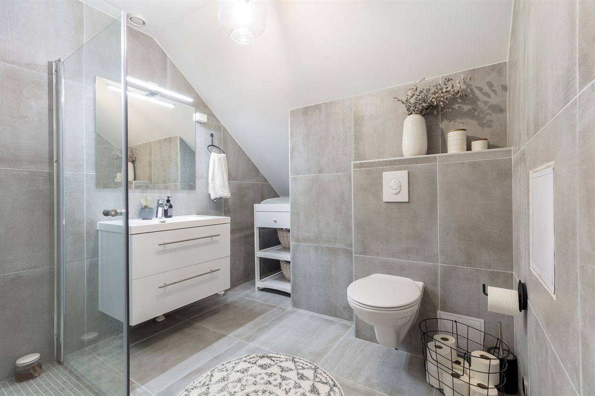 På badet i andre etasje er de store gulvflisene alternert med lysegrå mosaikkfliser på gulv i dusjsonen Galleribilde