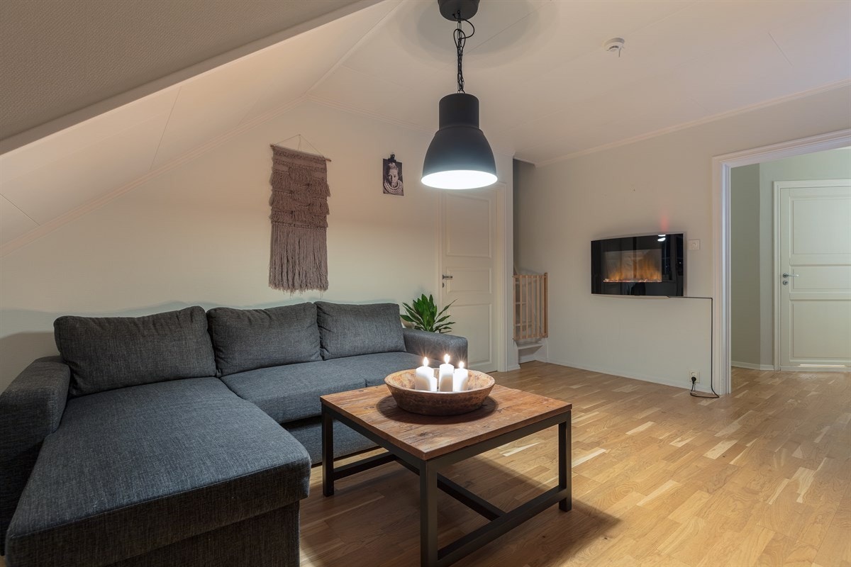 Stuen har parkettgulv og lysmalte vegger, pent oppbrutt av en mørkbeiset, panelt fondvegg. Galleribilde