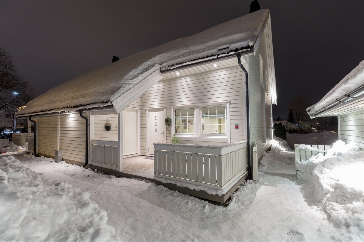 I forbindelse med inngangspartiet finnes det en koselig, delvis overbygd adkomstterrasse på ca. 10 kvm. Terrassen har downlights i takutspring, tremmegulv og hvitmalt rekkverk. Fra uteplassen er det direkte adkomst til utvendig bod på ca. 5 kvm. Galleribilde