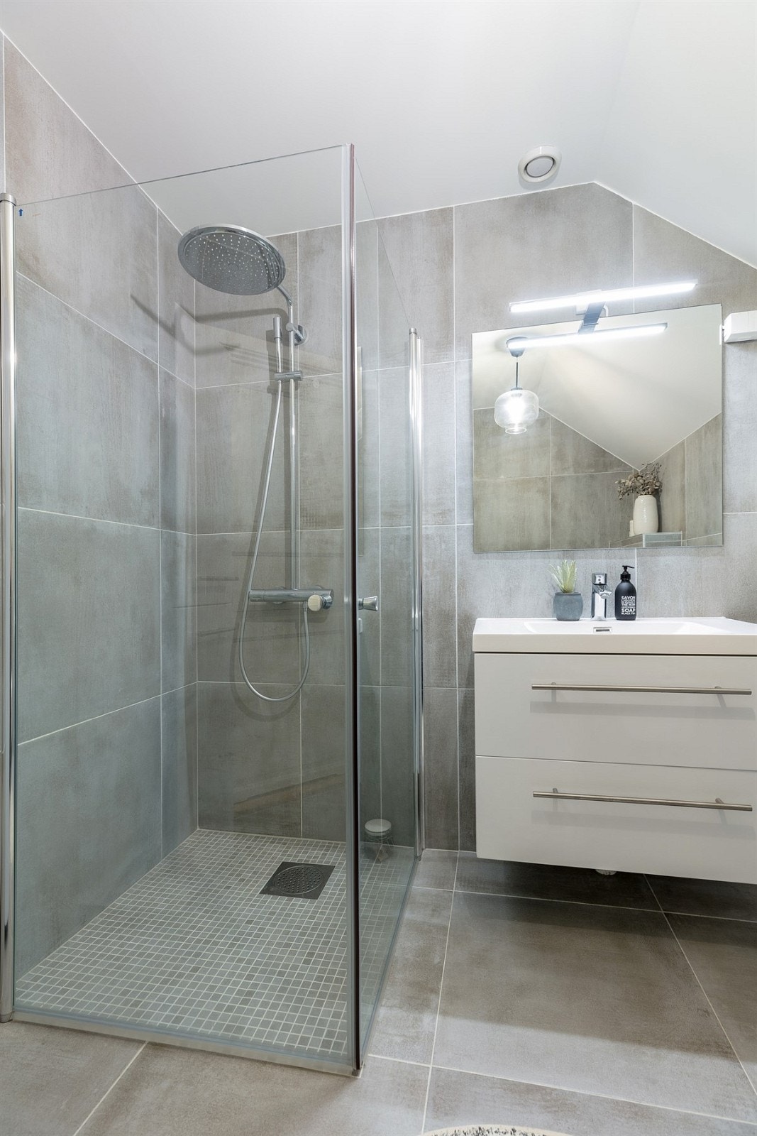 Det er montert speil med overlys og heldekkende servant på hvitt servantmøblement. Galleribilde