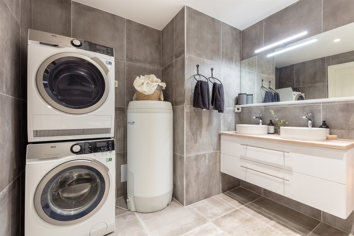 Badet i første etasje har speil med overlys, to toppmonterte servanter, hvitt servantmøblement og laminat benkeplate. Galleribilde