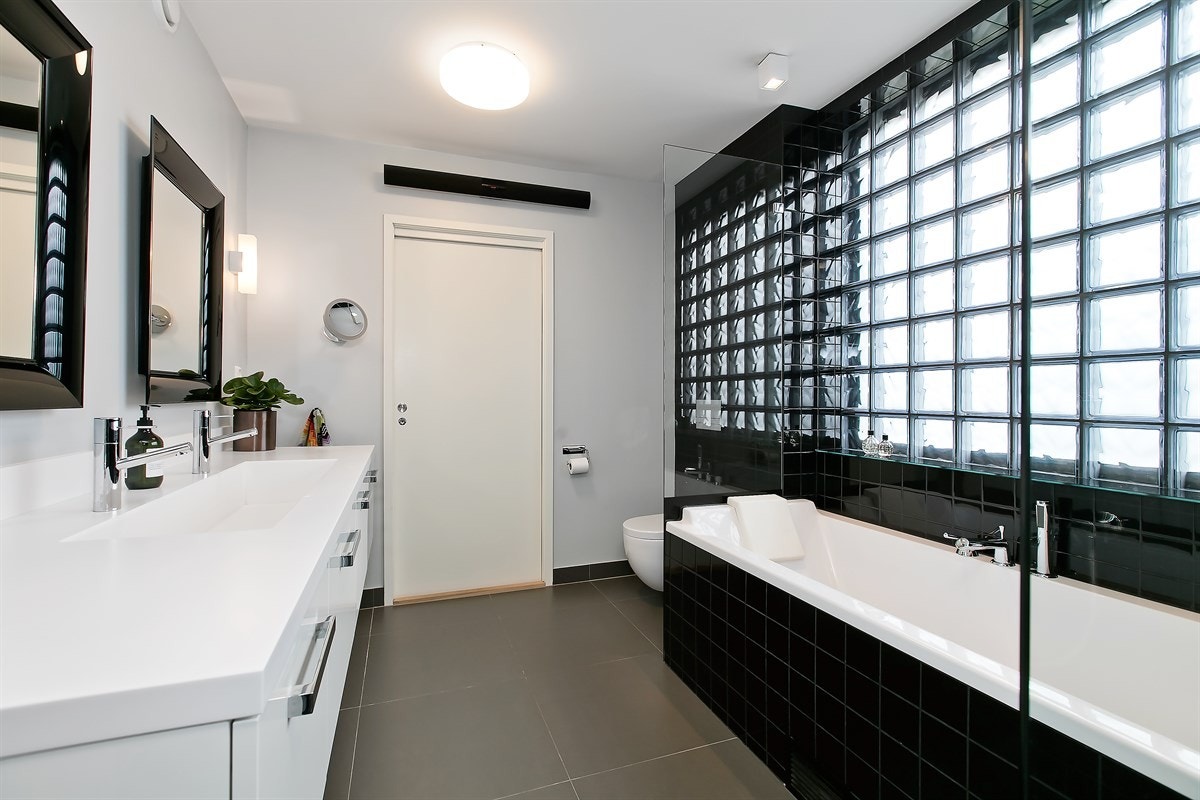 Badet har vannbåren varme i gulv, og fliser/malte flater. Glassbyggersten bak badekaret gir rommet mye naturlig lys Galleribilde