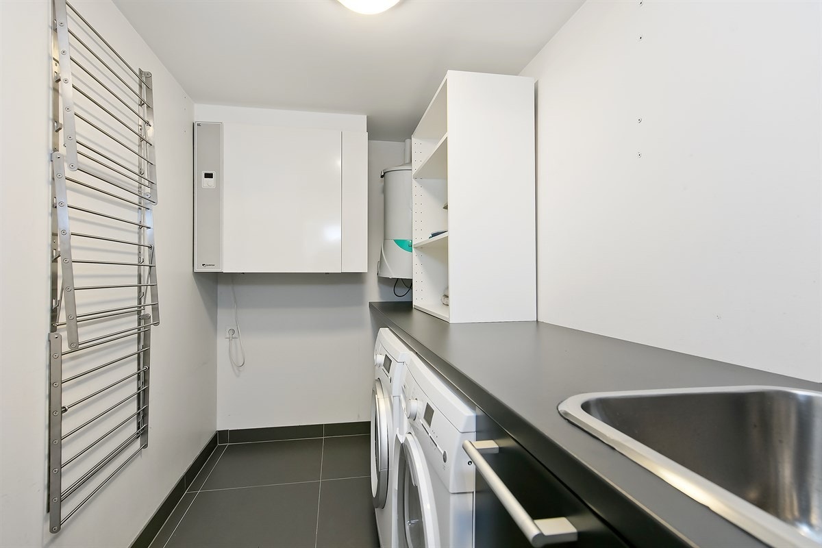 Meget praktisk vaskerom med benk- og skapinnredning fra Poggenpohl. Vegghengt tørkestativ. Opplegg til vaskemaskin og tørketrommel Galleribilde