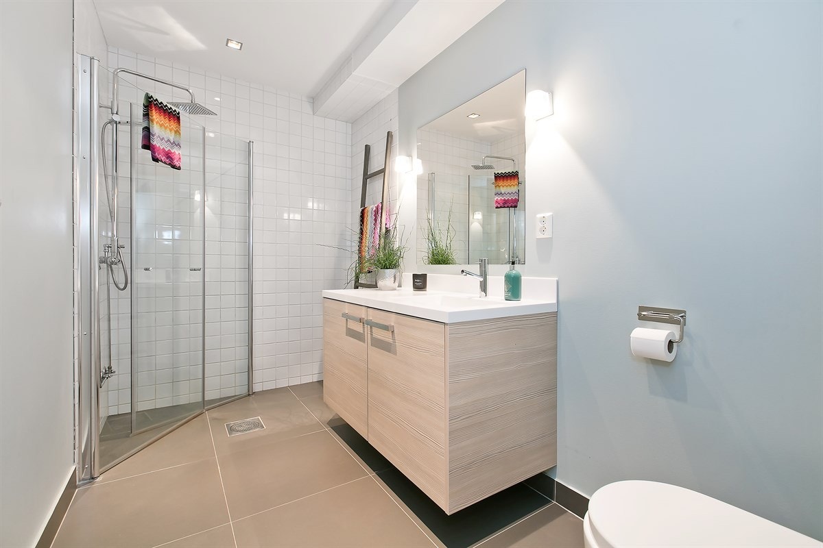 Delikat og innbydende bad i underetasjen, innredet med dusjhjørne, servant i innredning og toalett Galleribilde