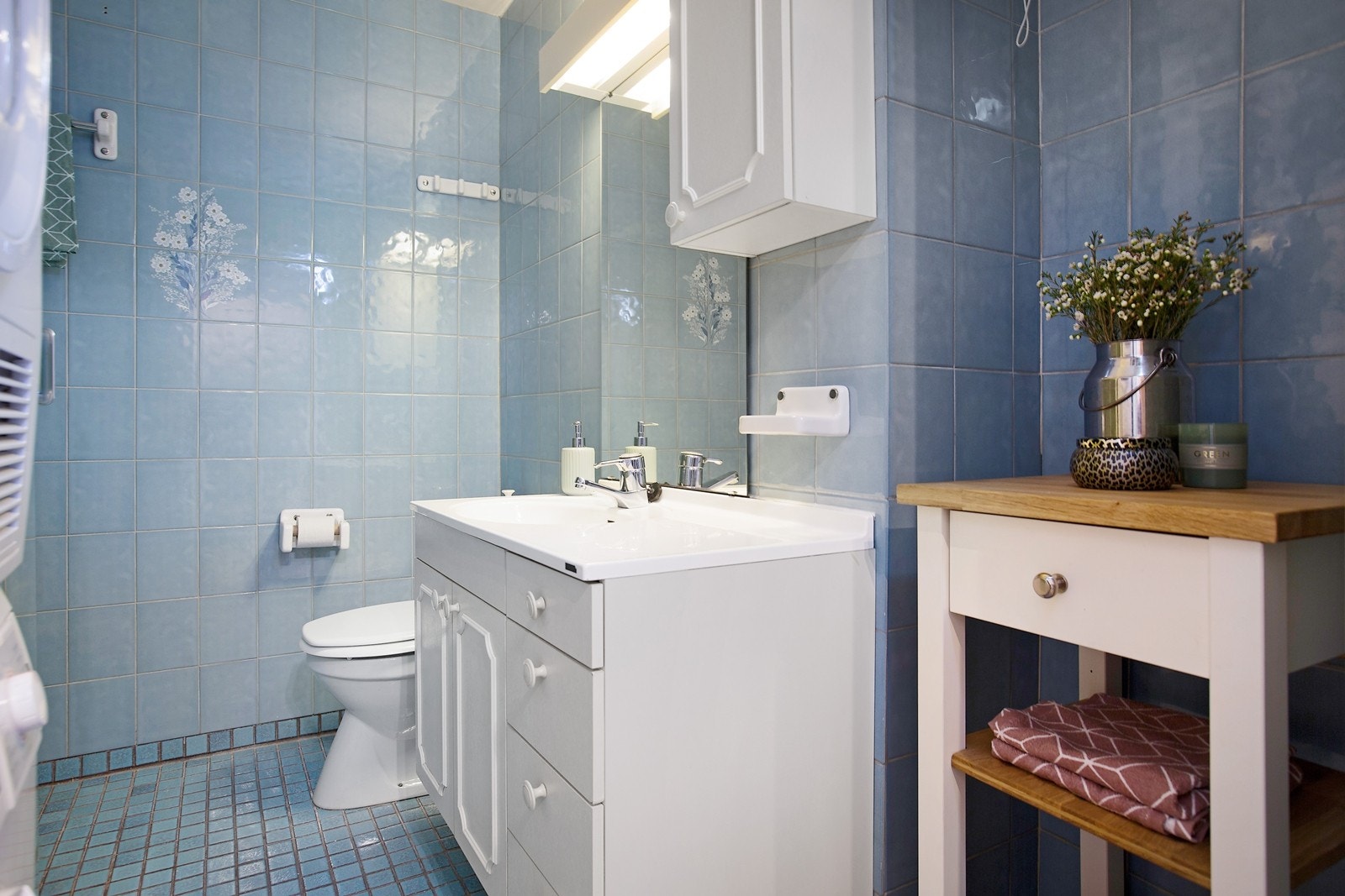 Romslig, flislagt baderom bestående av klosett, dusjkabinett, servant og servantskap. Oppl. for vask/tørk Galleribilde