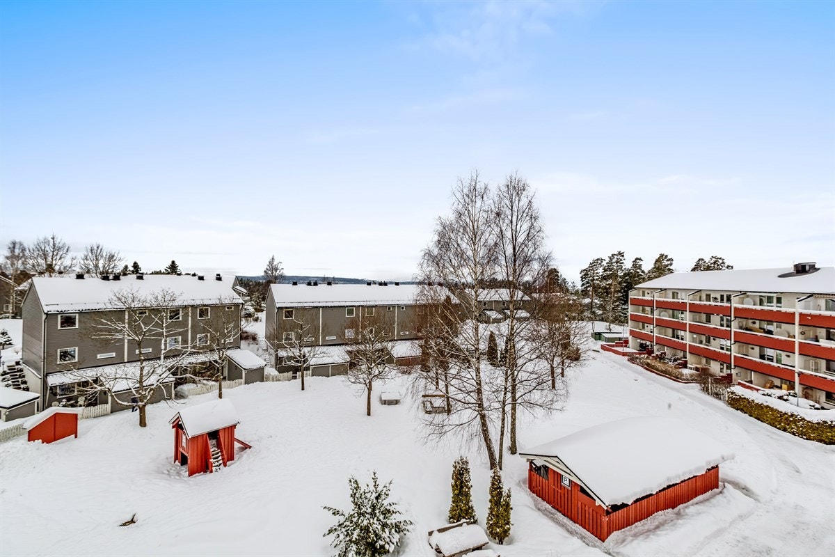 Etablert borettslag med bebyggelse som omkranser tun med lekeapparater og grøntareal Galleribilde