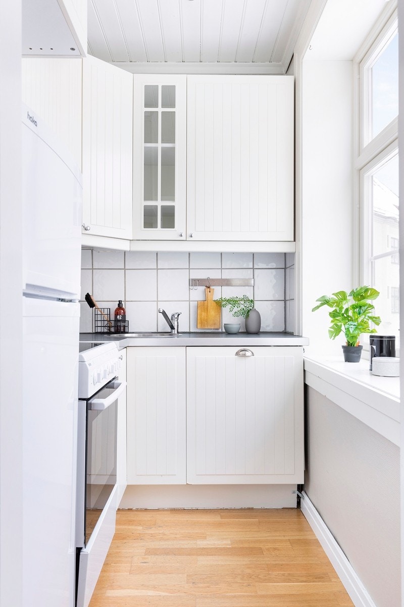 Kjøkkeninnredning med hvite profilerte fronter og glassskap. Videre er kjøkkenet utstyrt med frittstående komfyr, oppvaskmaskin samt kjøl og fryseskap. Galleribilde