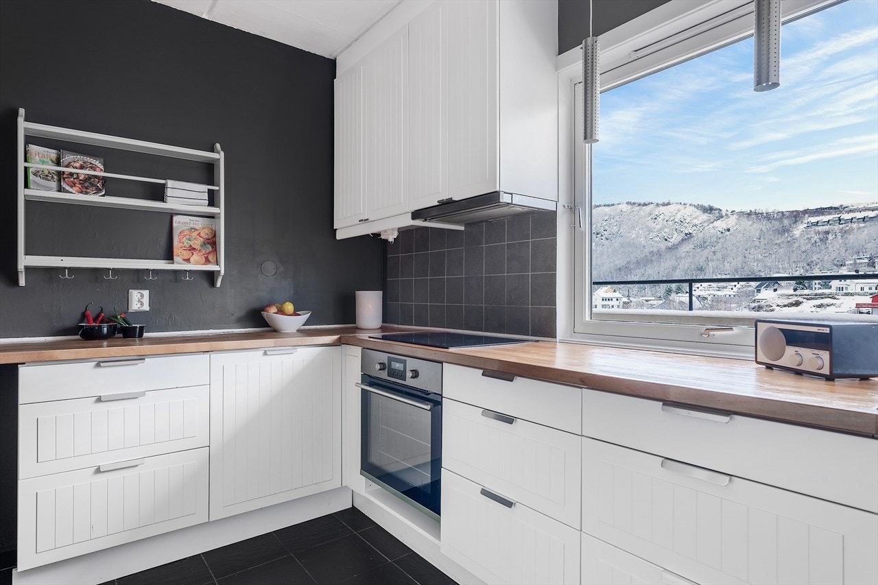 Kjøkkenet har profilerte fronter, benkeplate av tre og fliser på vegger over benk. Galleribilde