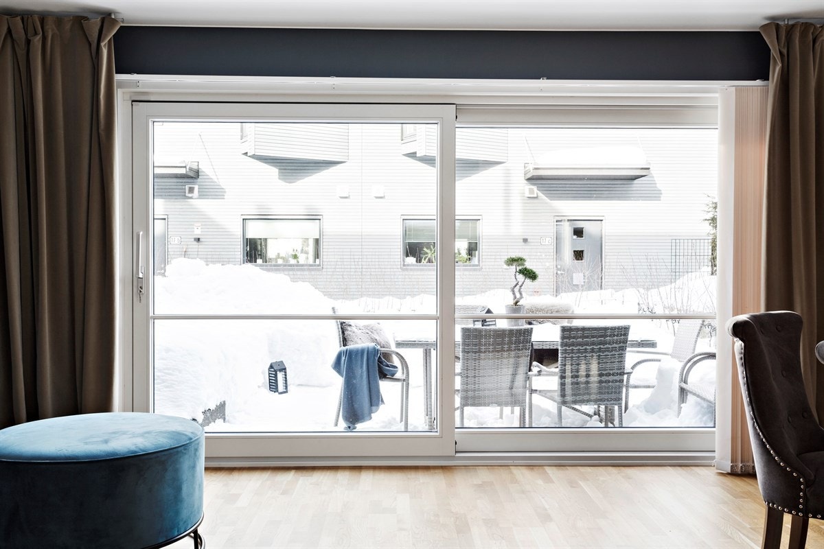 Store vindusflater i stue med utsyn mot terrasse og hage. Galleribilde