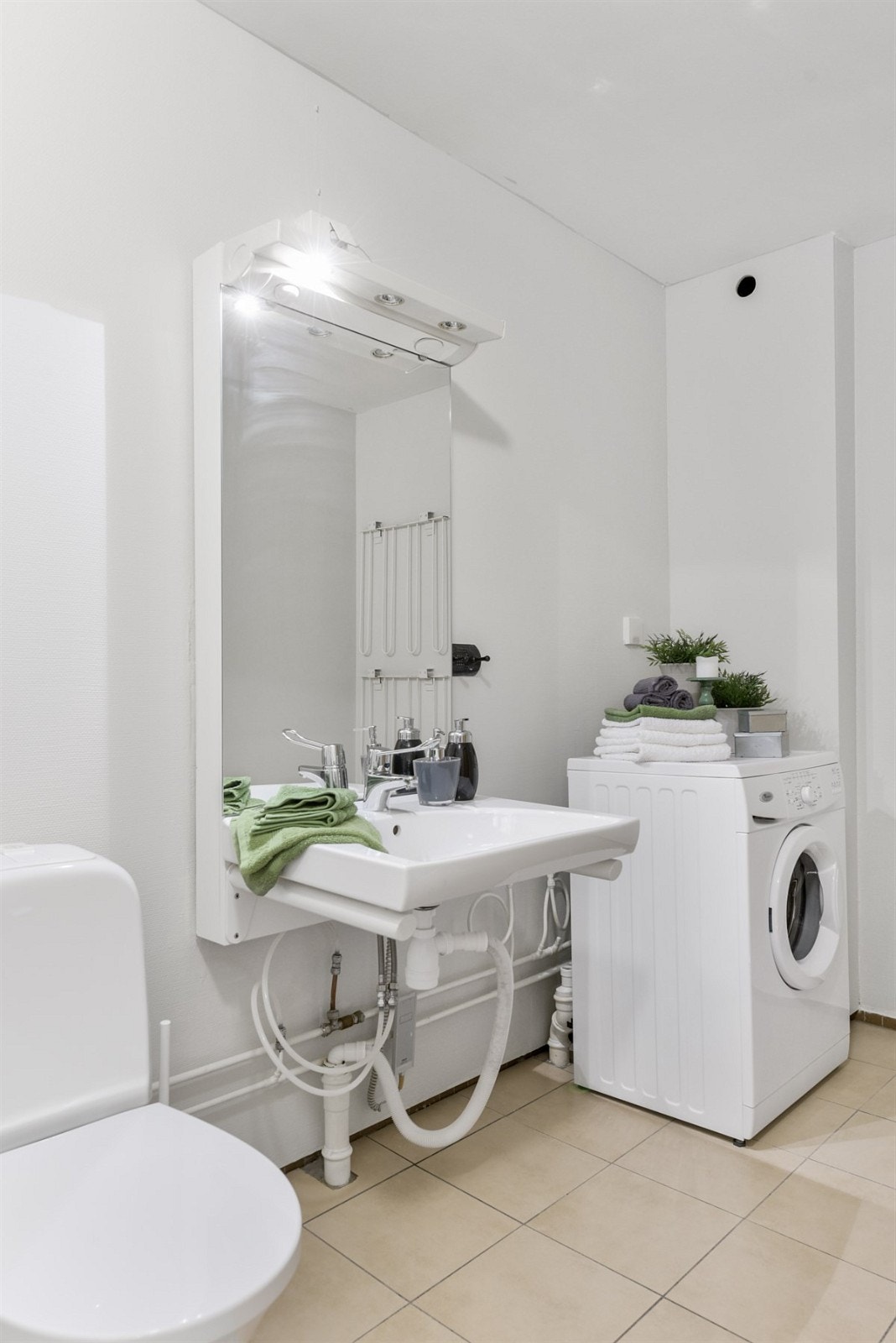 Baderom med klosett, servant, dusjsone og opplegg for vaskemaskin Galleribilde