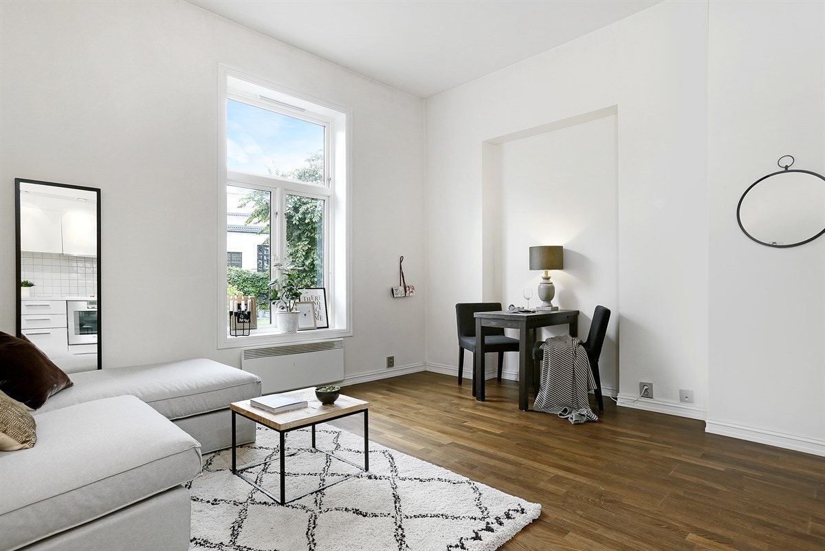 Stuen ligger i åpen løsning med kjøkkenet, har trestavs Merbau parkett på gulv, samt plass til sofa, tilhørende møblement og et frokostbord. Galleribilde