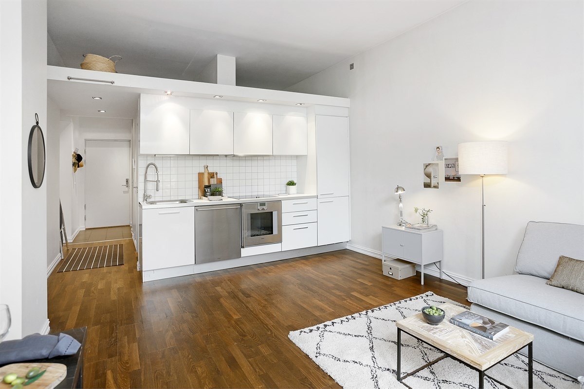 Stuen ligger i åpen løsning med kjøkkenet, har trestavs Merbau parkett på gulv, samt plass til sofa, tilhørende møblement og et frokostbord. Galleribilde