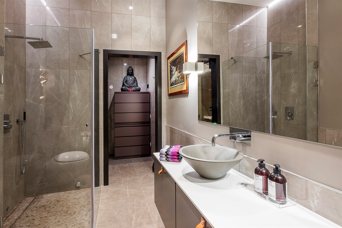 Bad med vegghengt WC, "skål" servant på Ballingslöv innredning med Corian benkeplate, dusj i hjørne med glassvegg. Galleribilde