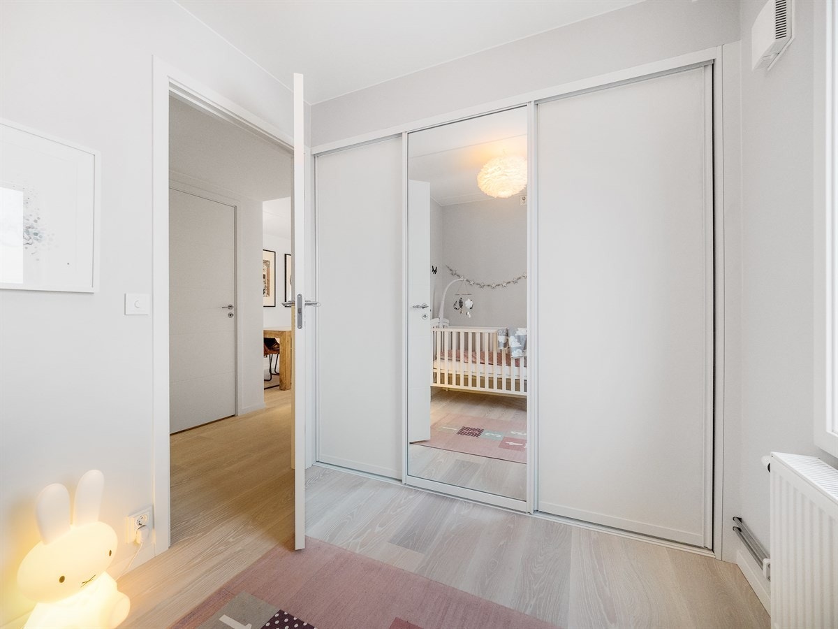 Fint og lunt soverom med skyvedørsgarderobe med speil, hyller, skuffesystem og hengere, som har rikelig med plass for oppbevaring. Galleribilde