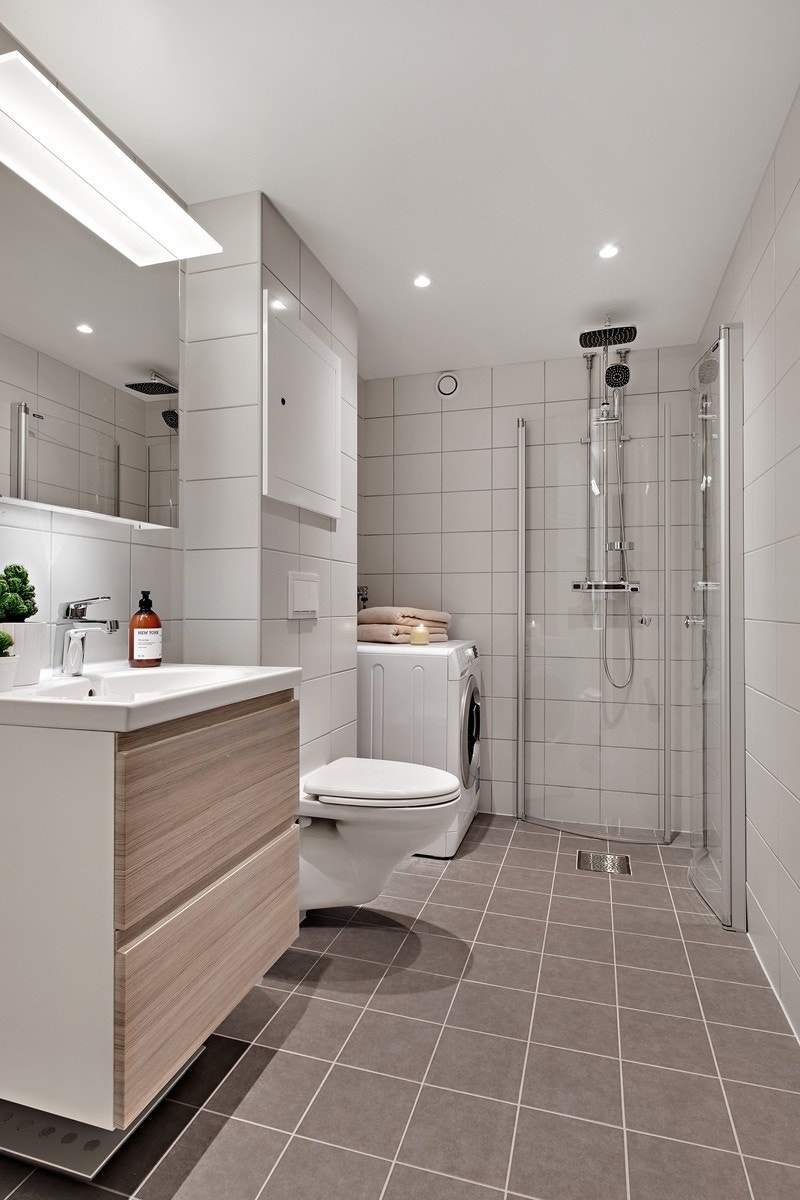 Badet har delikate fliser, flott baderomsinnredning og opplegg til vaskemaskin Galleribilde