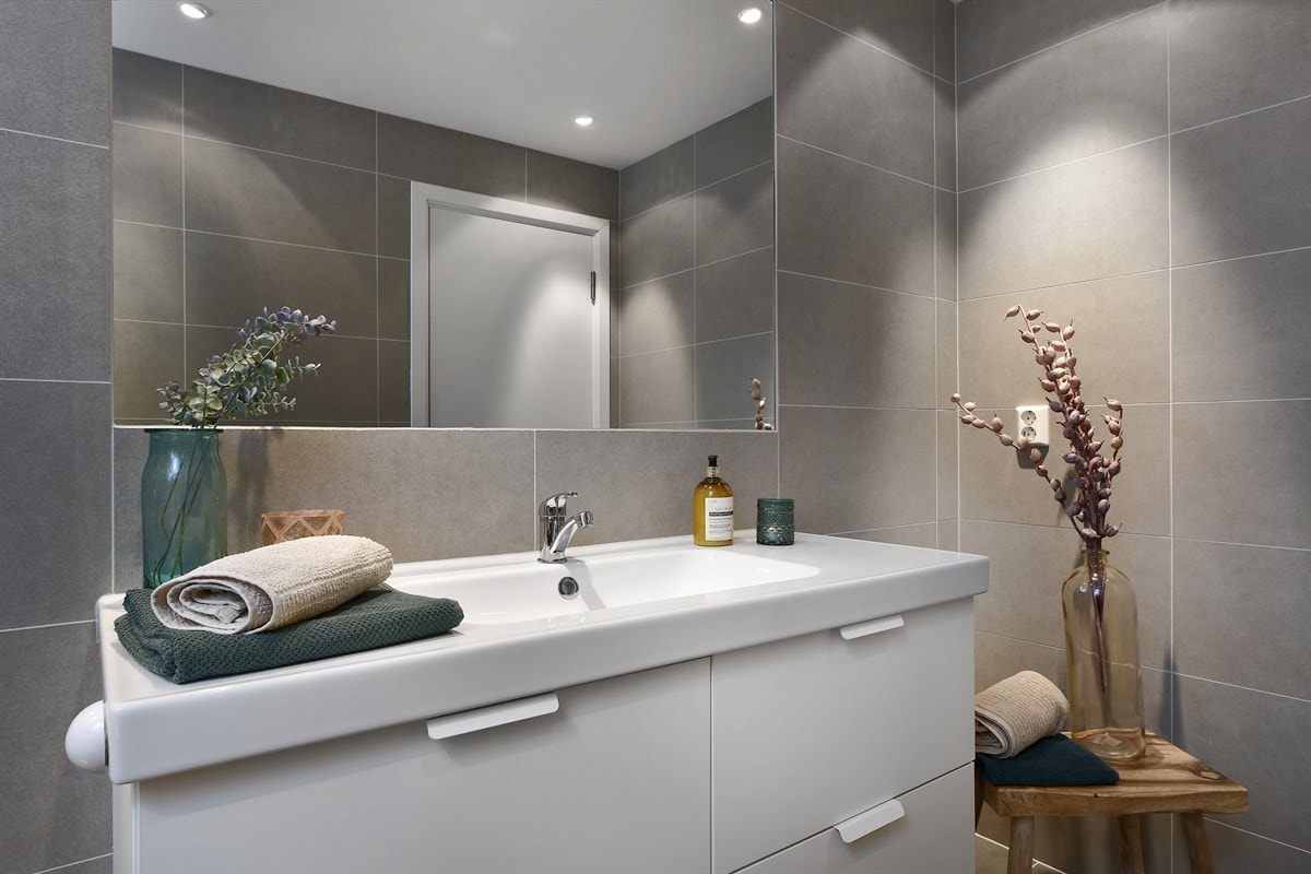 Videre er badet utstyrt med veggmontert toalett, dusjhjørne med deilig regnfallsdusj og opplegg for vaskemaskin/tørketrommel. Galleribilde
