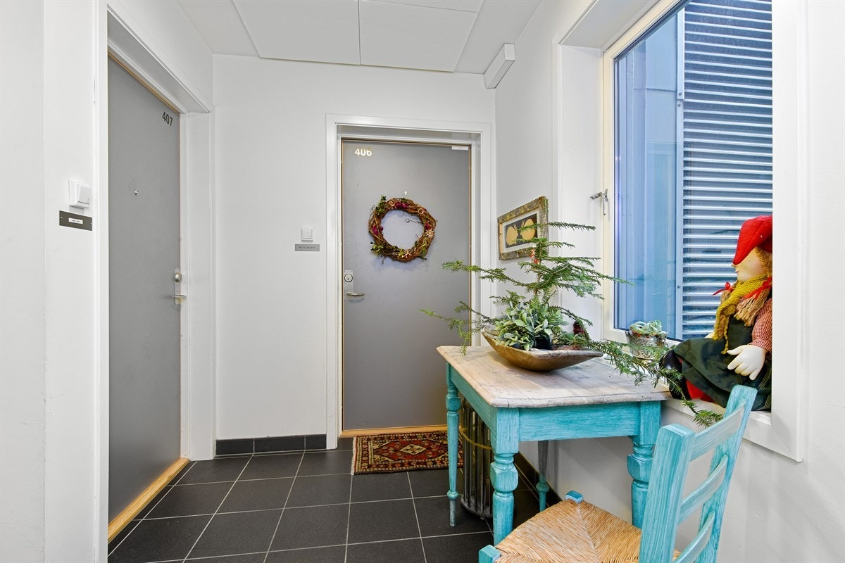 Fra en koselig fellesgang viser en gråmalt ytterdør veien inn til leilighetens stilrene entré. Galleribilde