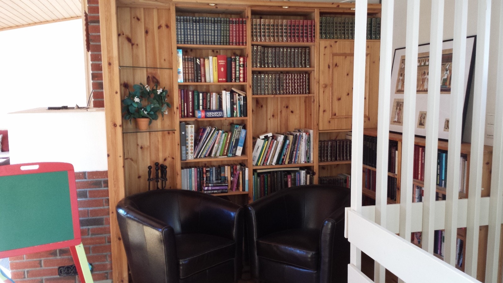 Stue sett fra trappen. Peis og bokhyller. Sikringsskap er bygget inn i seksjonen og har tredør til høyre. Ser mot nord. Galleribilde