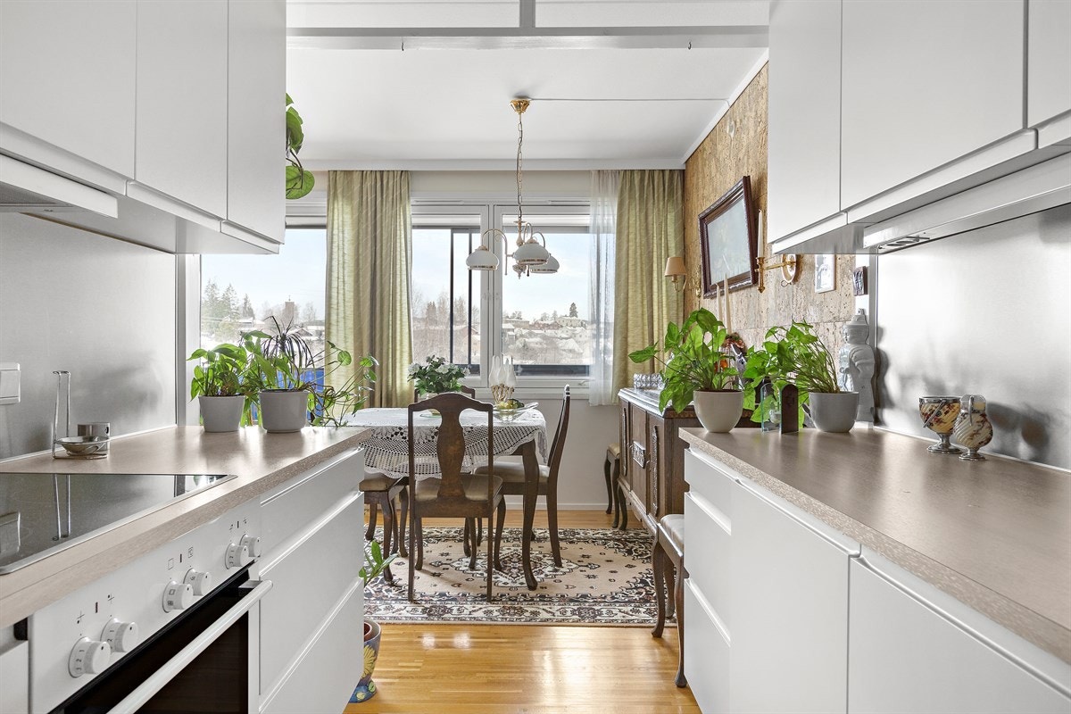 Innredningen er fra HTH og har glatte, hvite fronter med gripekant. Benkeplaten er i laminat treimitasjon, med en nedfelt dobbel oppvaskkum. Veggen overfor er kledd med stålplater som understreker den moderne stilen. Galleribilde