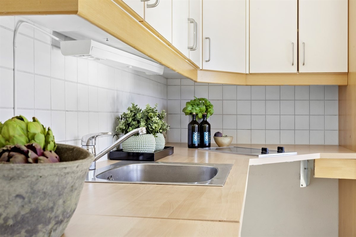 Fliser mellom overskap, laminert benkeplate og integrert koketopp. Galleribilde