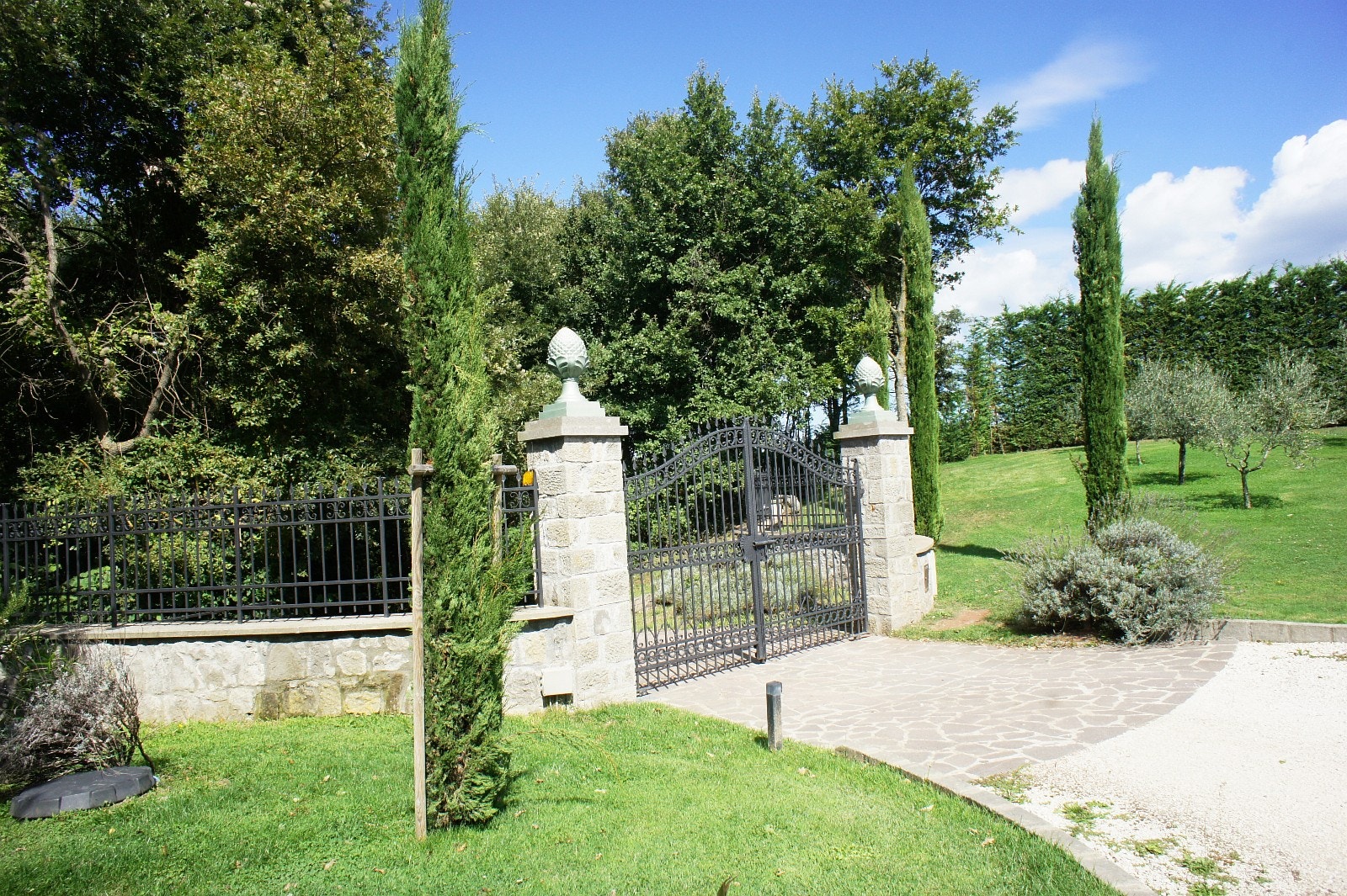 Elektrisk port. Sypresser rundt inngangsporten. Galleribilde