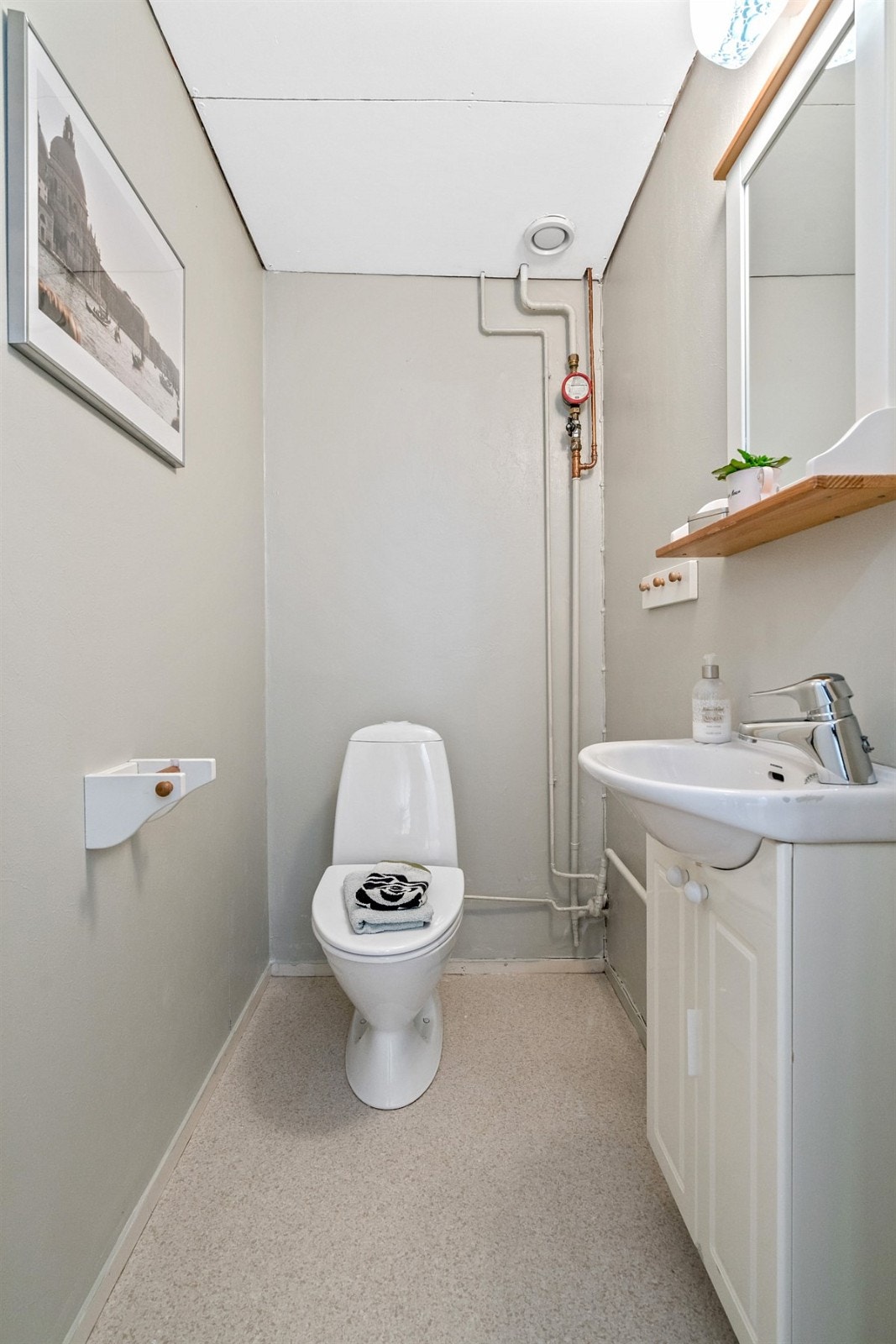 Vegg i vegg med badet er det separat toalettrom med wc og håndvask i skapinnredning Galleribilde