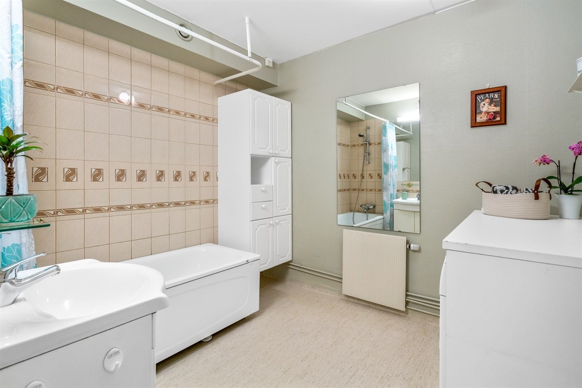 Romslig bad fra byggeår, med belegg på gulv og fliser på vegg i dusjsonen. Badekar med dusj og dusjforheng. Meget praktisk med benk over bla. vaskemaskinen! Galleribilde