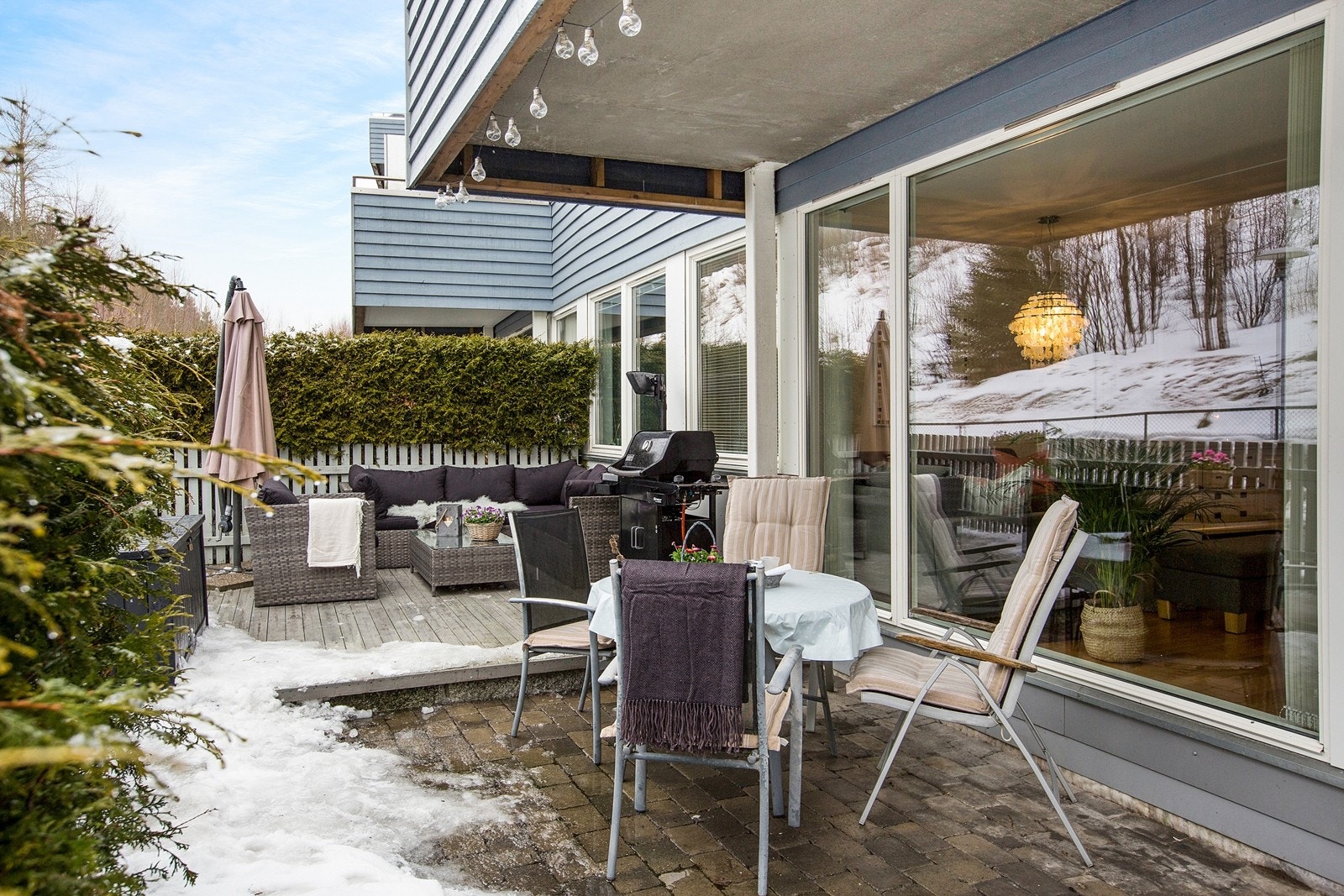 Markterrassen utenfor stuen er opparbeidet med både platting og belegningsten. Deler av uteplassen er under tak, som muligjør å sitte ute på tross av en liten skur Galleribilde